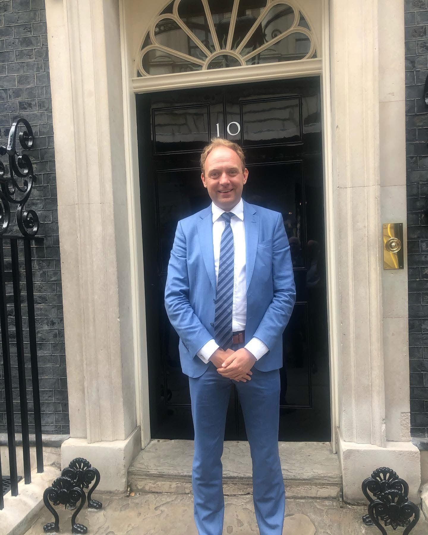 Daniel Fitzhenry in a blue suit outside the door of 10 Downing Street, July 2023