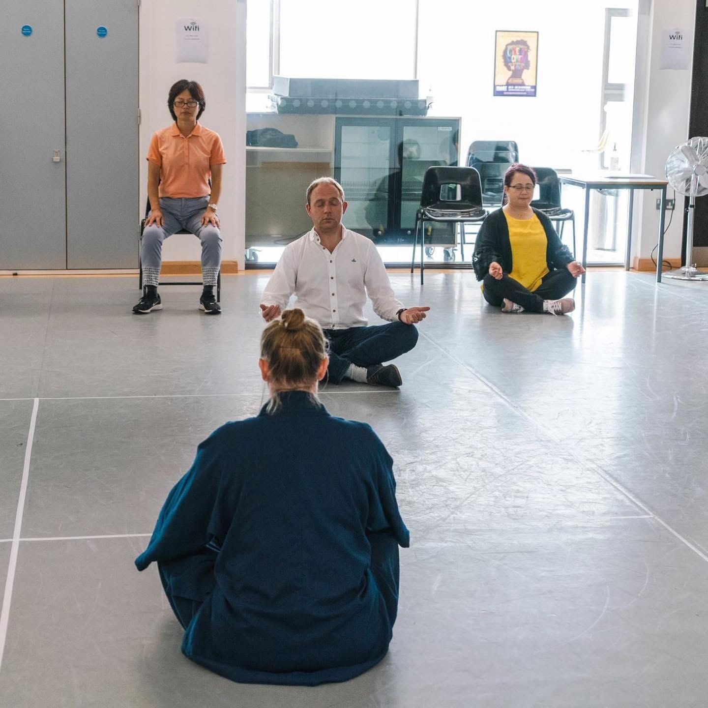 Daniel Fitzhenry meditating cross-legged with others at the Shaolin Centre, Southampton