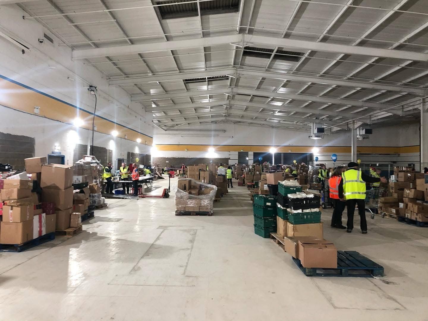 Volunteers in high-visibility vests sorting pallets of aid inside the Ukraine relief distribution centre, Southampton