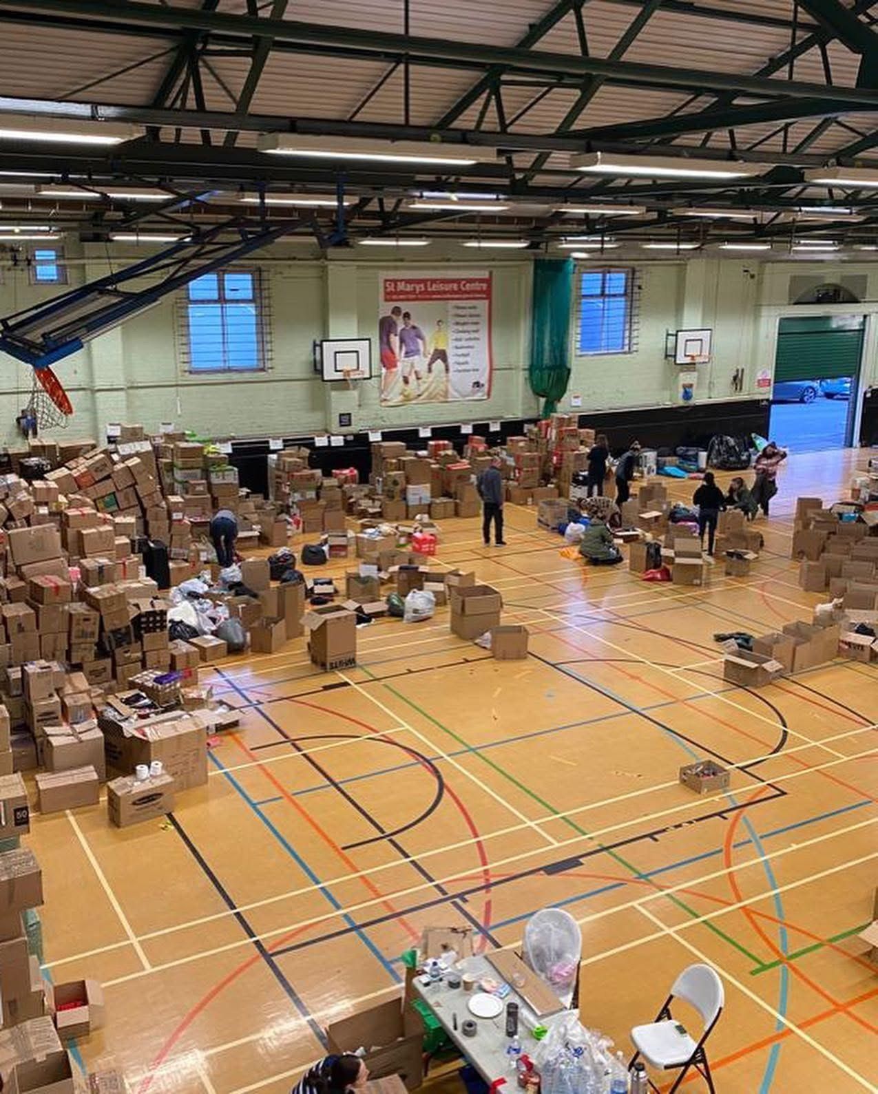 Volunteers sorting hundreds of boxes of donations for Ukraine across the sports hall floor at St Mary's Leisure Centre, Southampton